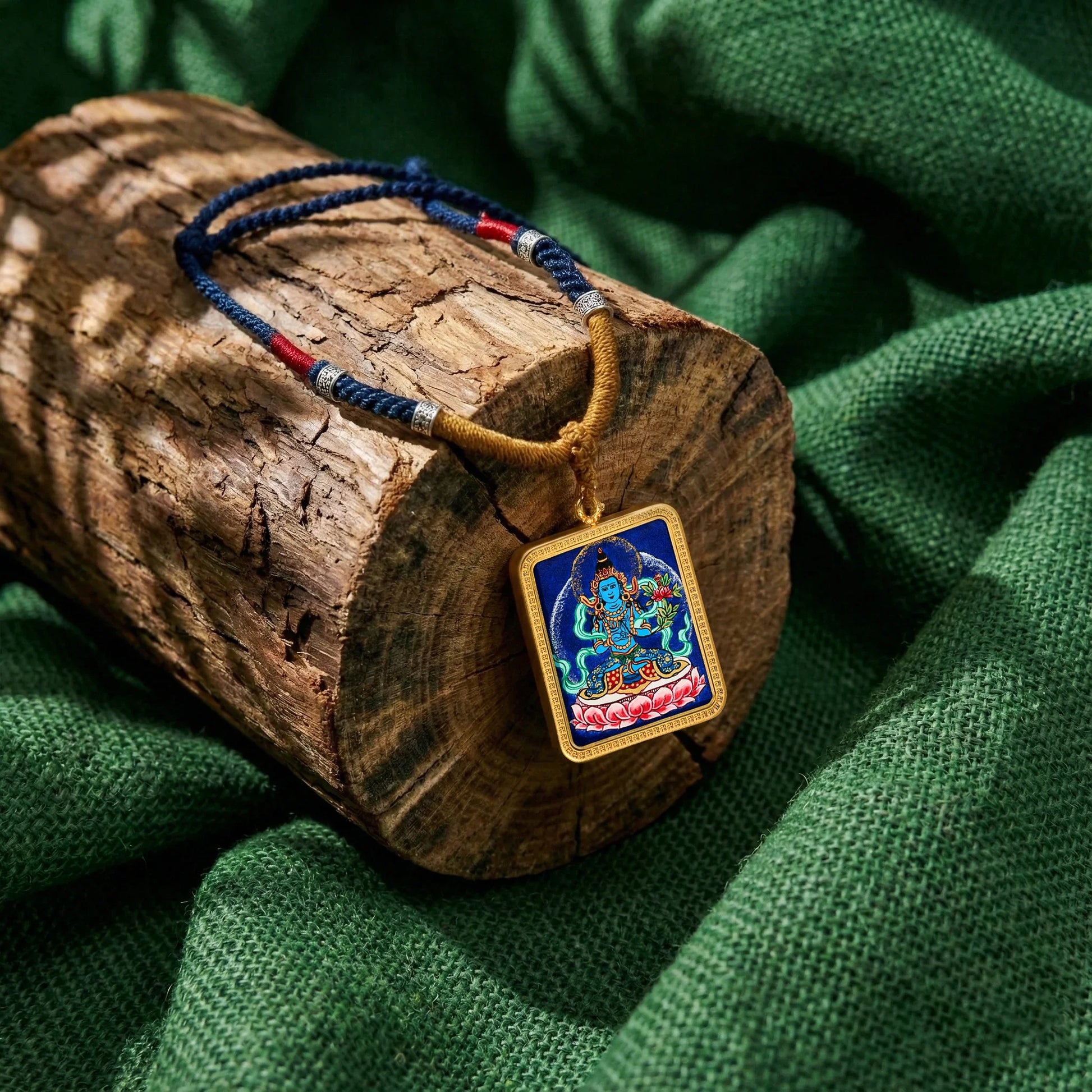 Himalayan spiritual necklace with colorful deity pendant on rustic wood and green fabric